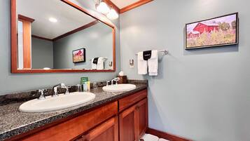 A bathroom with two sinks, a large mirror, and a framed picture on the wall.