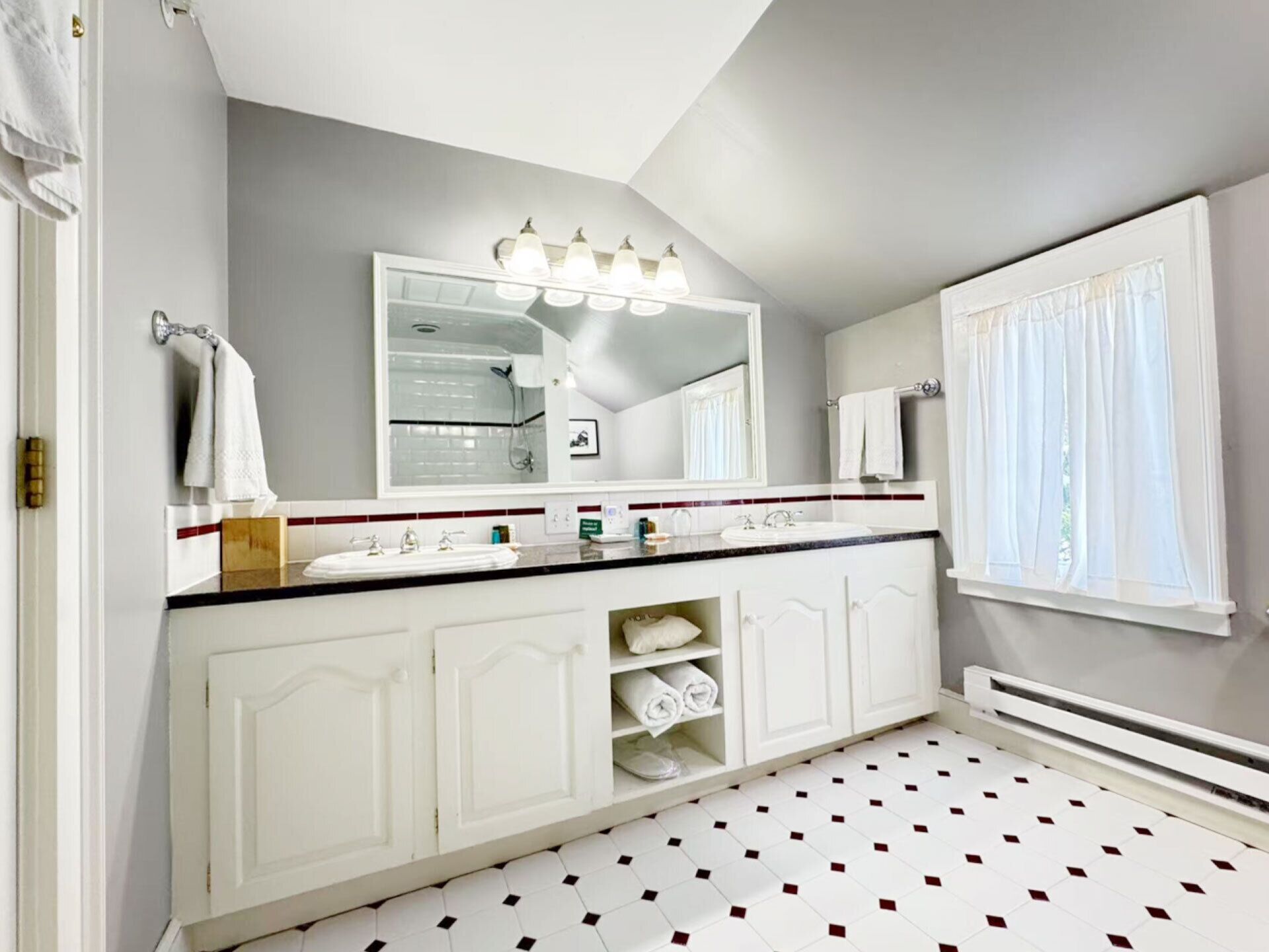 A bathroom with two sinks, a large mirror, and a shower.