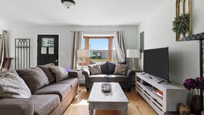 Un salon avec un canapé, une table basse, un téléviseur et une fenêtre avec des rideaux.