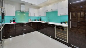 Une cuisine moderne avec des meubles de couleur sombre, un pare-feu turquoise et une lucarne.