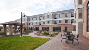 A multi-story building with a patio area featuring outdoor seating. - Spacious Accessible Studio w/ Walk-In Shower (Oconomowoc)