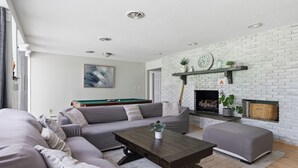 A modern living room with a grey sofa, a coffee table, and a fireplace with a brick wall.