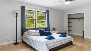 A bedroom with a bed, a bedside table, a lamp, a window with curtains, and a closet.