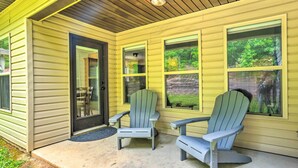 Une véranda avec deux fauteuils Adirondack et une porte.
