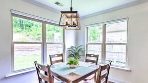 Un coin repas avec une table en bois, quatre chaises et un luminaire suspendu.