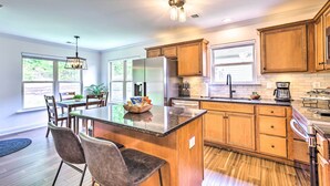 Une cuisine moderne avec des meubles en bois, un îlot central et un coin repas comprenant des chaises et une table.