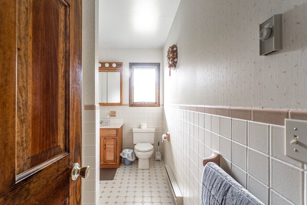 A bathroom with a wooden door, a toilet, a sink, and a towel rack. - 3BR Chalet 5 mins to Skiing with Hot Tub, Fireplace & Mountain Views (Windham)