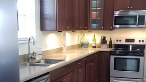 Una cocina con armarios de madera oscura, un refrigerador de acero inoxidable, un microondas integrado, un horno y un lavavajillas.