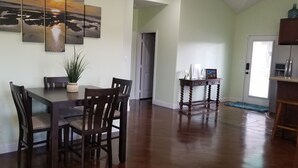 Un comedor con una mesa y sillas de madera, una planta en maceta y un cuadro en la pared.