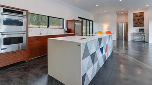 A modern kitchen with built-in appliances, a central island, and large windows. - Asheville Meadows Pool, Hot Tub & Forest Views (Asheville)