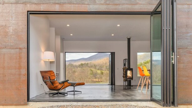 A modern interior with a large glass door leading to a scenic outdoor view. - Asheville Meadows Pool, Hot Tub & Forest Views (Asheville)