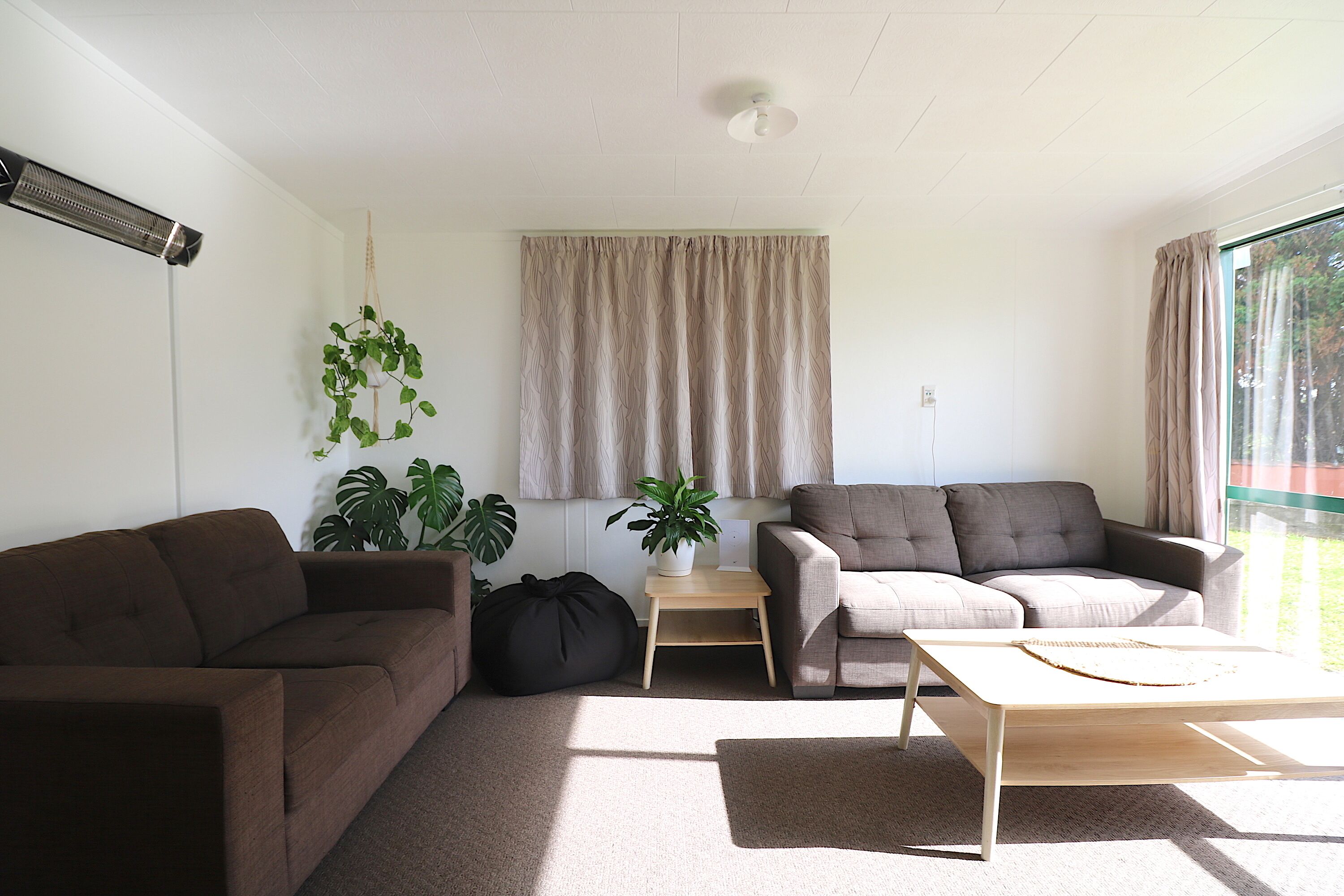 Un salon avec deux canapés, une table basse et une petite table d’appoint sur laquelle est posée une plante.