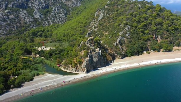 Vue aérienne d’une zone côtière avec une plage, des falaises rocheuses et une végétation luxuriante.