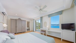 Une chambre avec un lit, un bureau, une télévision et une vue sur la mer.