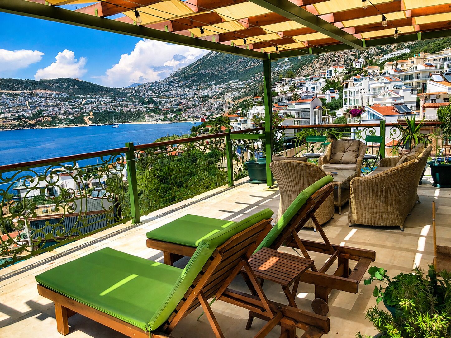 Una terrazza con mobili da esterno, vista su una cittadina costiera e una montagna sullo sfondo.