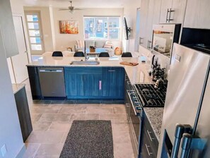 Enjoy cooking in this well-lit kitchen with a central island, sink, stainless steel refrigerator, and gas stove.