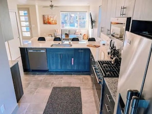 Enjoy cooking in this well-lit kitchen with a central island, sink, stainless steel refrigerator, and gas stove.