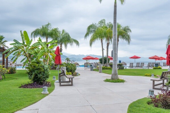 A resort with a pool, lounge chairs, and palm trees.