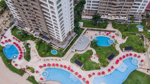 Un resort con múltiples piscinas, un tobogán acuático grande y zonas de playa con sombrillas.