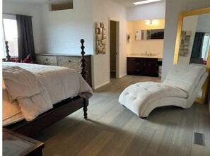 Relax in this serene bedroom with a large bed and comfortable reading chair.