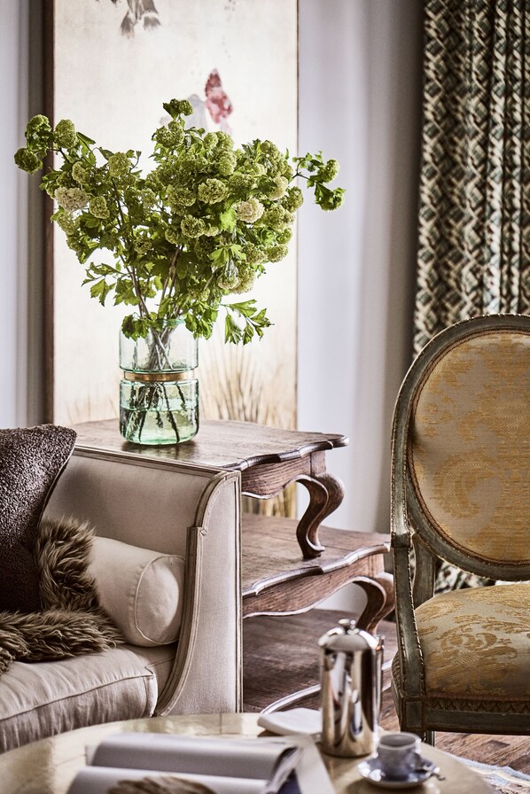 Relax in style with a plush sofa, armchair, and vintage side table, perfect for unwinding in comfort.