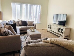 Relax in this inviting living space with a comfortable sofa, flat-screen TV, and large window.