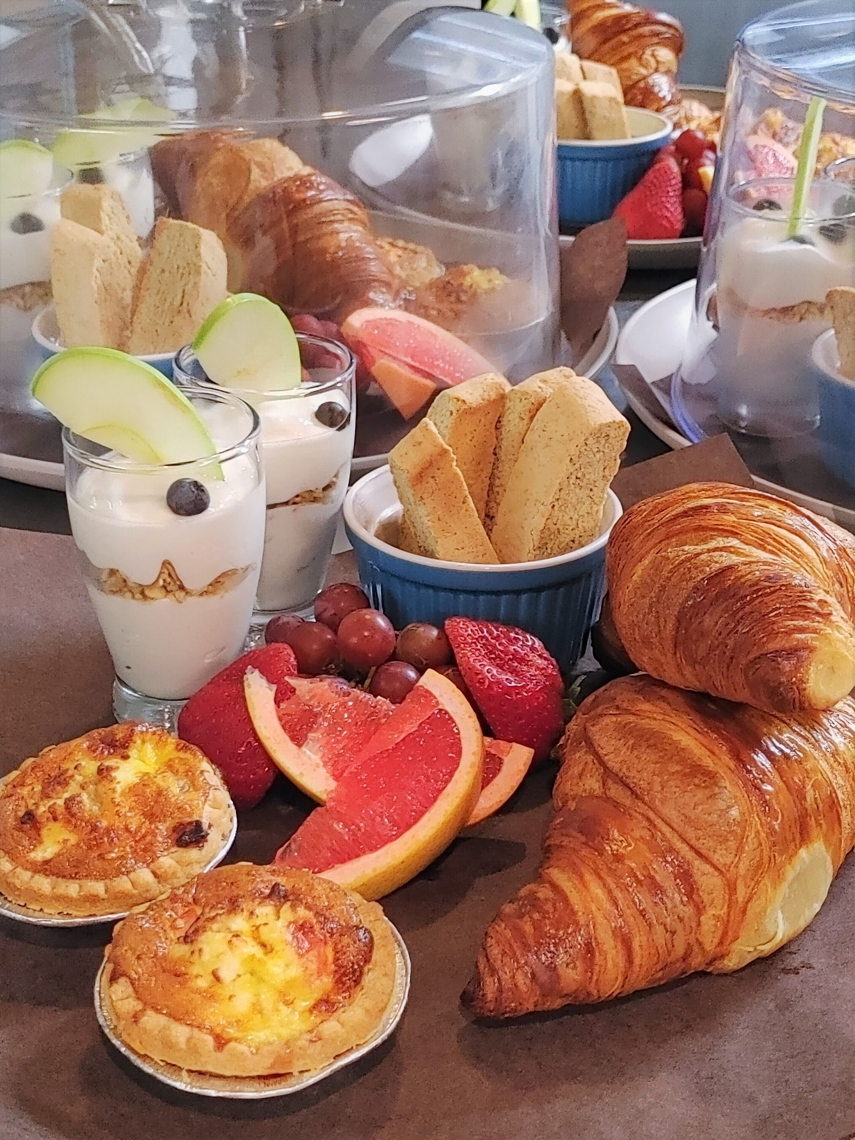 Un bufé de desayuno con diversos pasteles, frutas y bebidas.