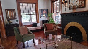 A cozy living room with a fireplace, a sofa, a coffee table, and a bookshelf. - Stonewater Manor (Gananoque)