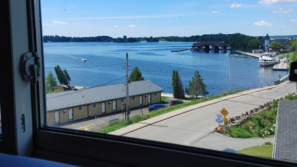 A view of a waterfront area with a building, a dock, and boats. - Stonewater Manor (Gananoque)