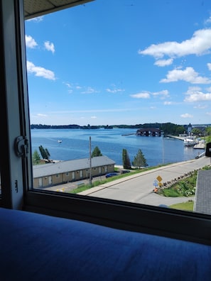 A view of a waterfront area with a building, a dock, and boats. - Stonewater Manor (Gananoque)
