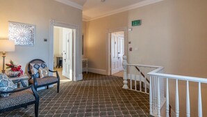 Un hall de hotel con piso estampado, una escalera y una silla con cojín decorativo.