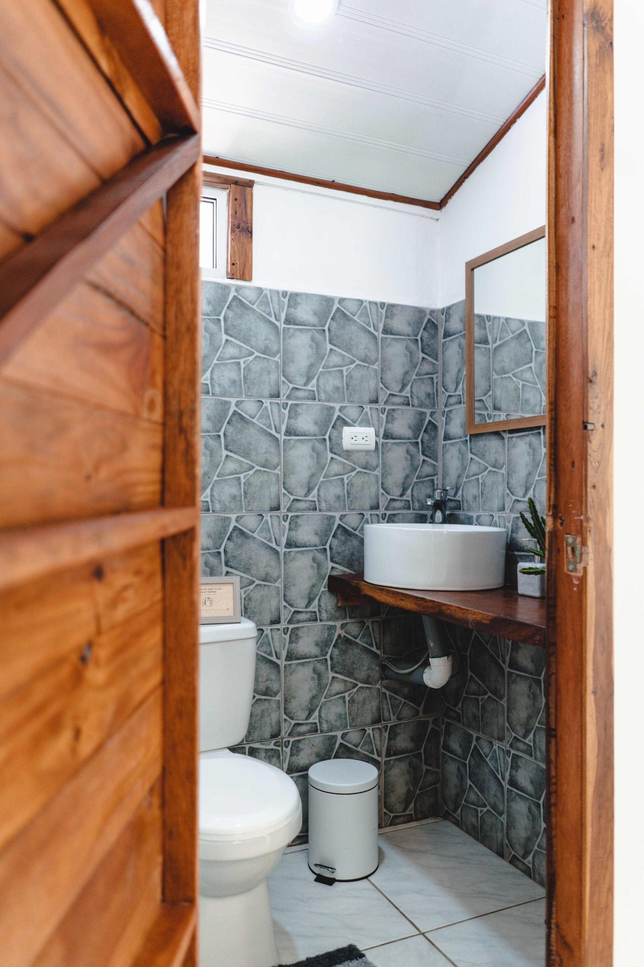 A bathroom with a stone wall, a white sink, and a toilet.