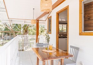 Une table en bois avec des chaises, un set de table en fibres tressées et un verre de jus d’orange.