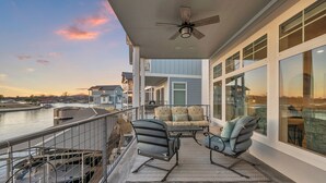 A balcony with a view of the water, a ceiling fan, and a seating area with a rug. - Reel Oasis, family-friendly, pet friendly, pool, boat slip, golf and on lake LBJ (Kingsland)