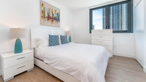 Une chambre moderne avec un lit, des tables de chevet, une commode et une fenêtre avec des stores.