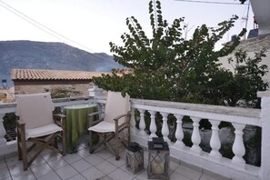 A terrace with two chairs and a table, a white balustrade, and a view of a mountain.
