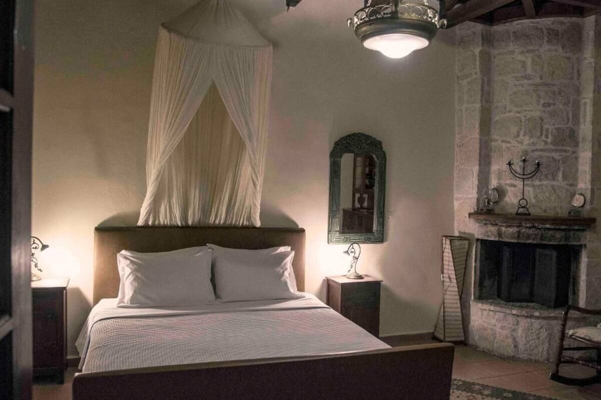 Une chambre à coucher avec un lit à baldaquin, une cheminée en pierre et un miroir au mur.