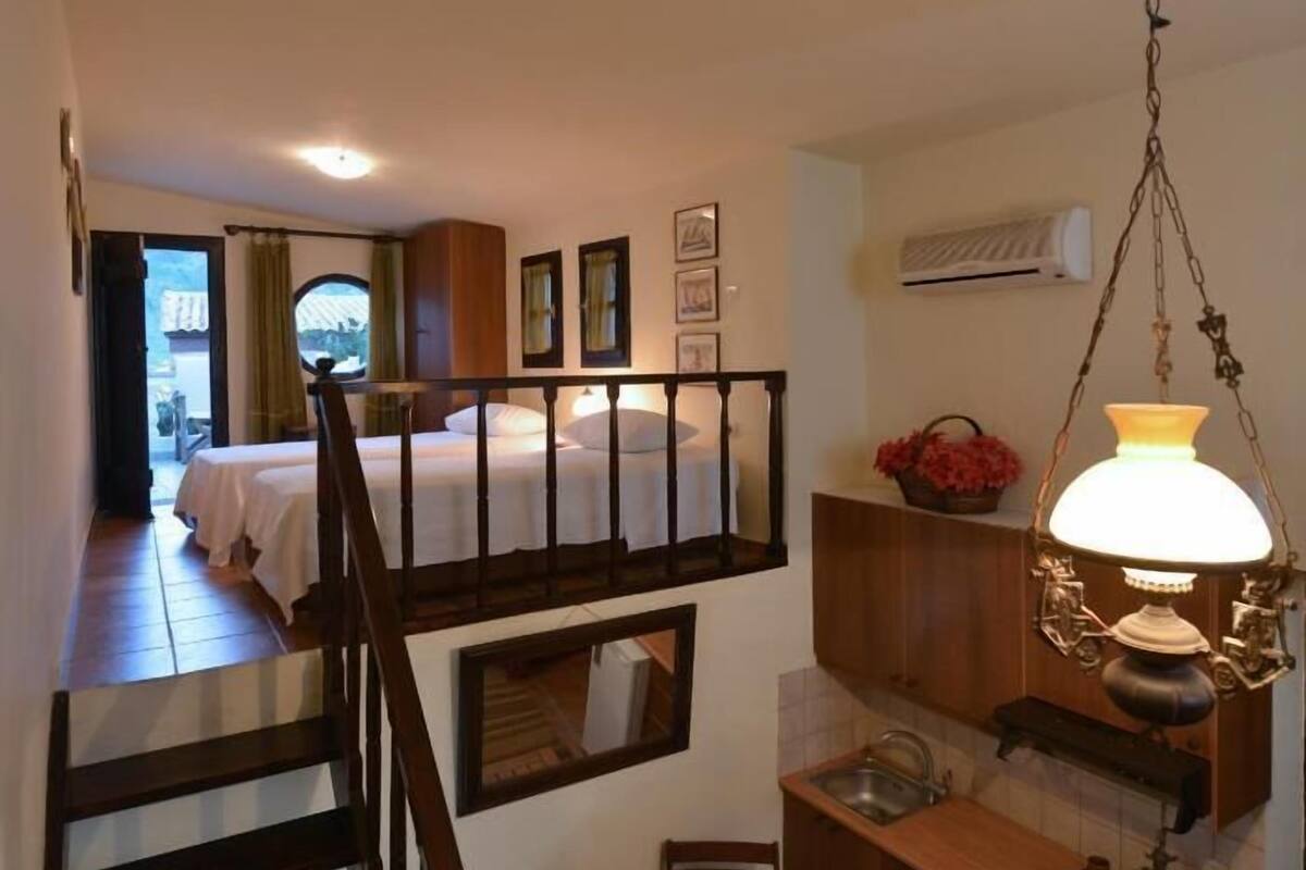Une cuisine compacte avec un escalier en bois, un petit coin repas et une chambre avec un lit et une fenêtre.