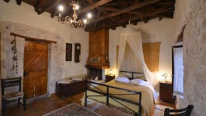 A rustic bedroom with a wooden bed, a canopy, a wooden wardrobe, and a chandelier. - Troullos Traditional Houses (Archanes-Asterousia)