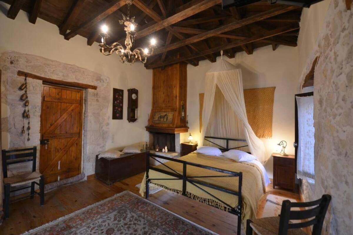 Une chambre à coucher rustique avec un lit en bois, un baldaquin, une armoire en bois et un lustre.