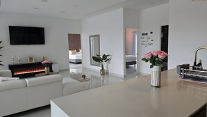 A modern living room with a fireplace, white sofas, a TV, and a large mirror. - Villa cipresso Monteverde (Monteverde)