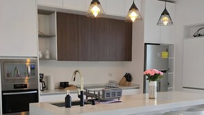 A modern kitchen with a central island, pendant lights, and a built-in oven. - Villa cipresso Monteverde (Monteverde)