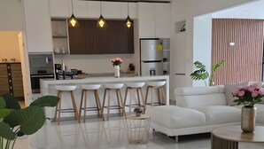 A modern kitchen with white cabinets, a central island with stools, and pendant lighting. - Villa cipresso Monteverde (Monteverde)