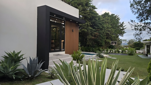A modern house with a large glass window, a basketball court, and a well-maintained lawn. - Villa cipresso Monteverde (Monteverde)