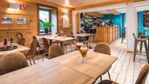 Un restaurant chaleureux avec un décor intérieur en bois, des tables avec des chaises et un coin bar.