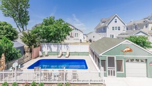 Zona residencial com piscina, quintal cercado e casas ao fundo.