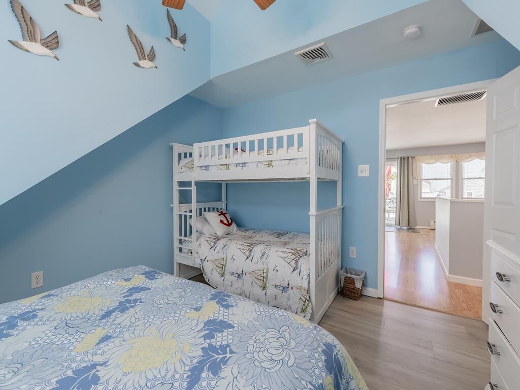 Un dormitorio con literas, una cama grande con ropa de cama floral y un techo decorado con calcomanías de pájaros.