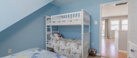 Un dormitorio con literas, una cama grande con ropa de cama floral y un techo decorado con calcomanías de pájaros.