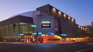 Ein modernes Gebäude mit großer Glasfassade, einem gut sichtbaren 'LIVE NATION'-Schild und einem hell erleuchteten Eingangsbereich.