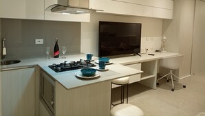 Moderni keittiö, jossa on kaasuliesi, televisio ja baaritiski jakkaroineen.